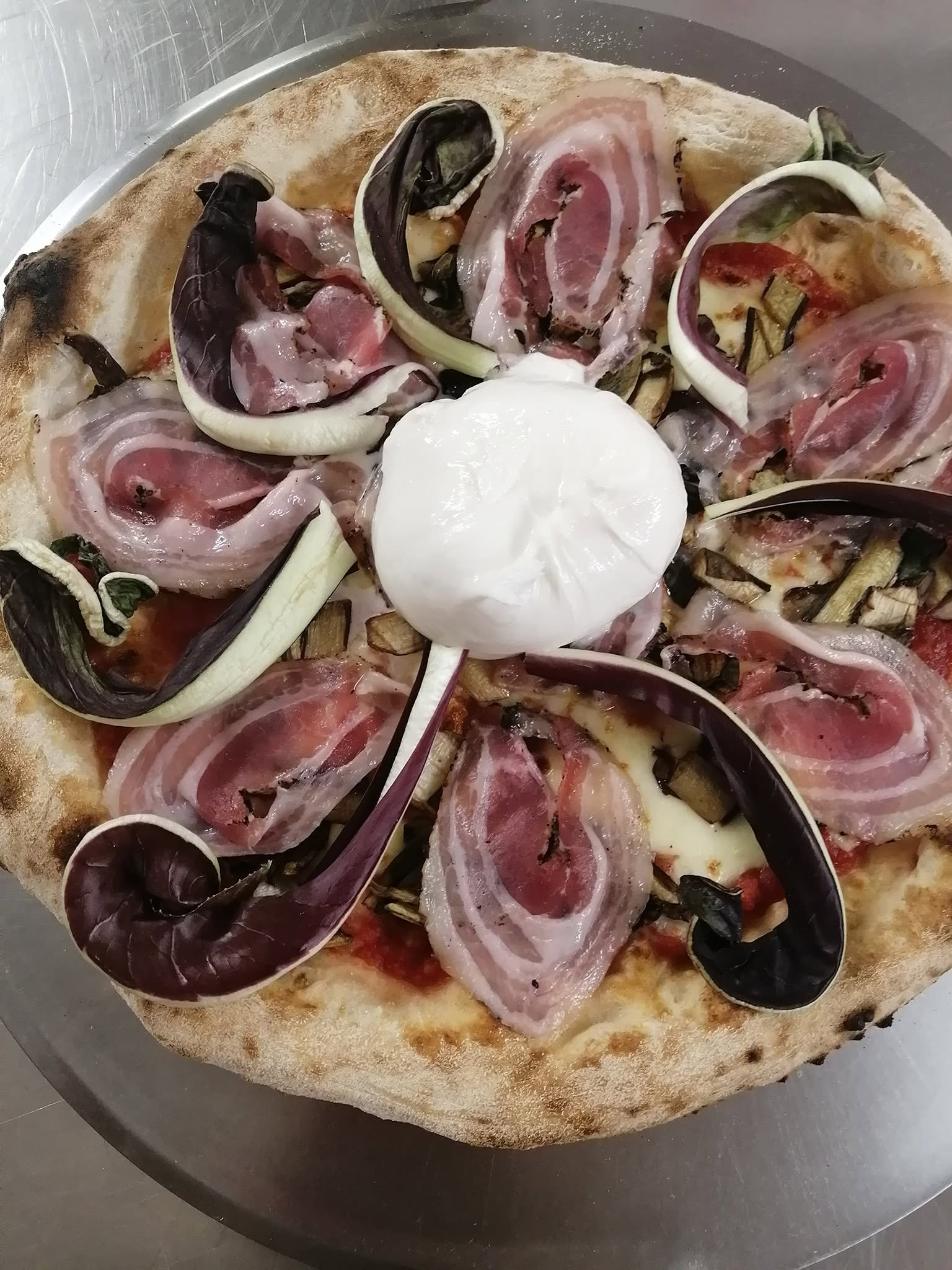 Pizza gourmet artistica con radicchio tardivo arricciato, pancetta arrotolata a petalo, melanzane e grande burrata centrale